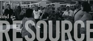 black and white photo of a group of people talking in a library